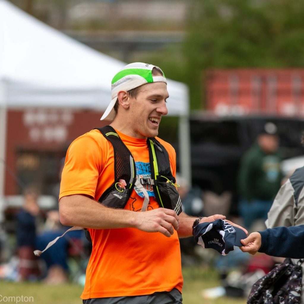 Hyner Trail Challenge Finisher picks up new Hyner Hat while wearing his old one.