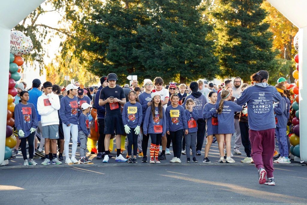 Runners eager to take off at the starting line in their branded race shirts.